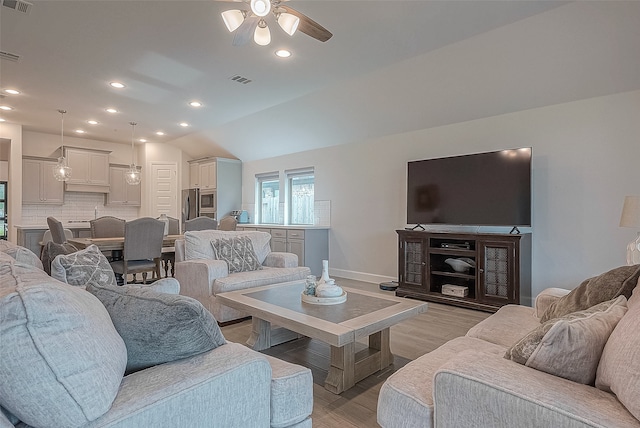 living room featuring ceiling fan, vaulted ceiling, and light wood-type flooring