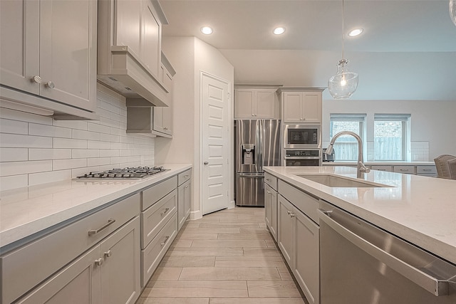 kitchen with appliances with stainless steel finishes, sink, gray cabinetry, decorative light fixtures, and ventilation hood