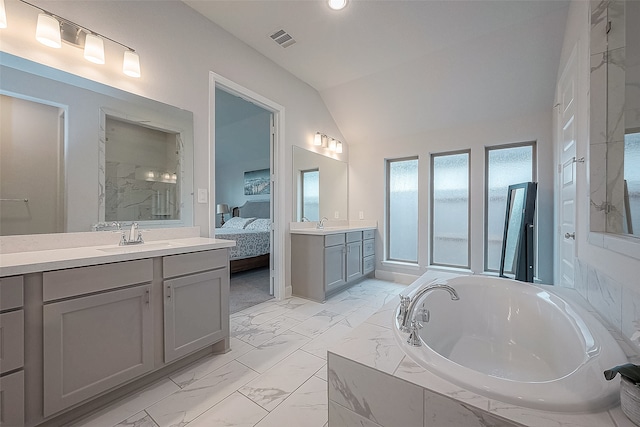 bathroom featuring vanity, lofted ceiling, and tiled bath