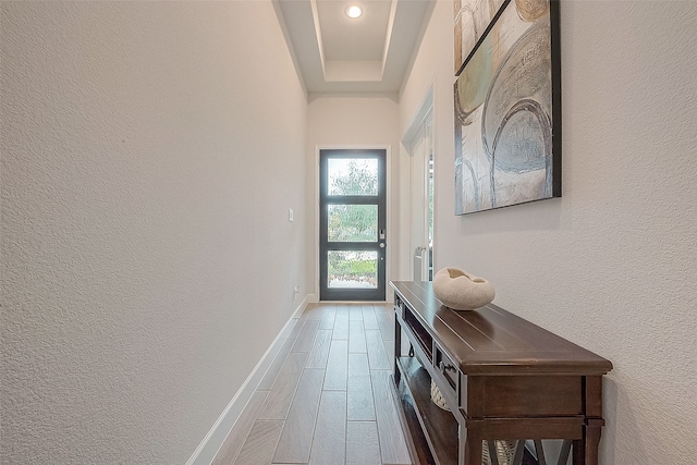 doorway to outside with hardwood / wood-style flooring and a raised ceiling