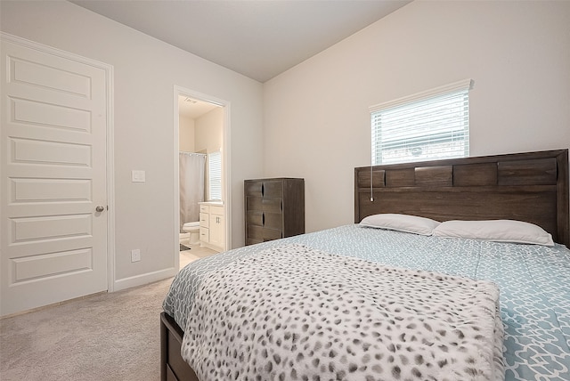 carpeted bedroom featuring ensuite bath and vaulted ceiling