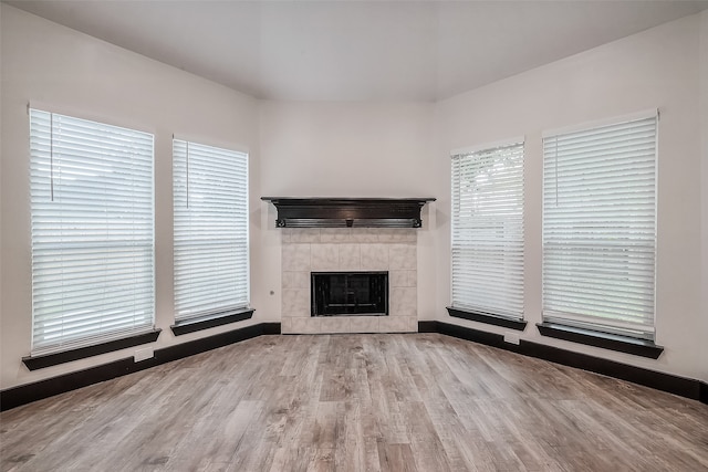 unfurnished living room with a tiled fireplace and light hardwood / wood-style floors