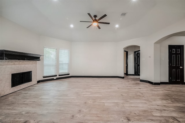 unfurnished living room with a fireplace, lofted ceiling, ceiling fan, and light hardwood / wood-style flooring