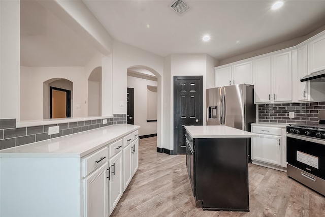 kitchen featuring stainless steel appliances, white cabinetry, light hardwood / wood-style flooring, a kitchen island, and decorative backsplash