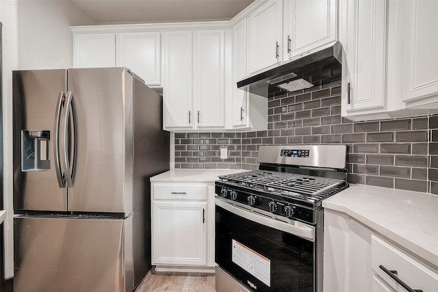 kitchen with stainless steel appliances, white cabinetry, light stone counters, tasteful backsplash, and light hardwood / wood-style flooring