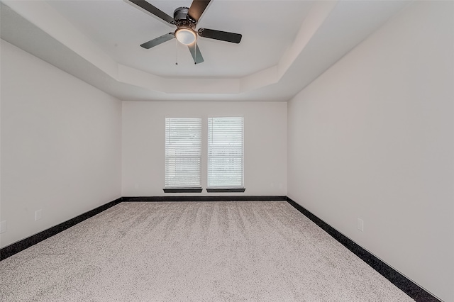 empty room featuring ceiling fan, carpet flooring, and a tray ceiling