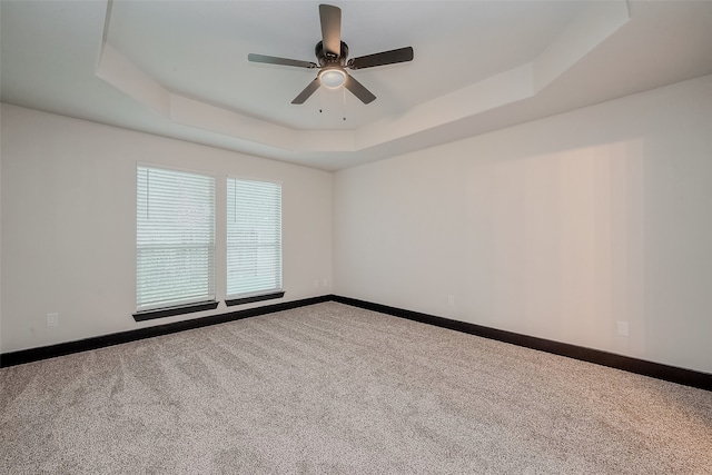 carpeted spare room featuring ceiling fan and a tray ceiling