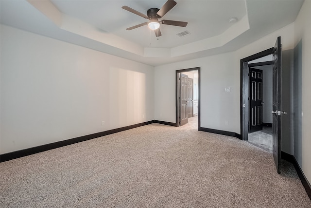 unfurnished room with light colored carpet, ceiling fan, and a raised ceiling