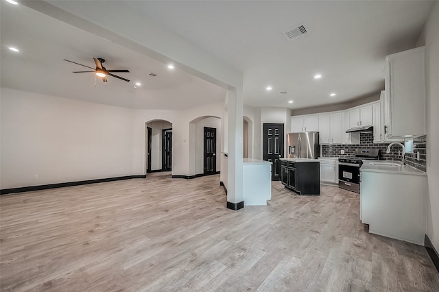 kitchen featuring stainless steel appliances, light hardwood / wood-style floors, a center island, tasteful backsplash, and ceiling fan