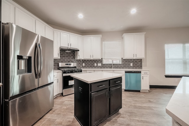 kitchen with stainless steel appliances, white cabinetry, backsplash, a kitchen island, and light wood-type flooring