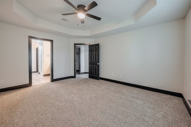 unfurnished bedroom featuring light colored carpet, ceiling fan, and a raised ceiling