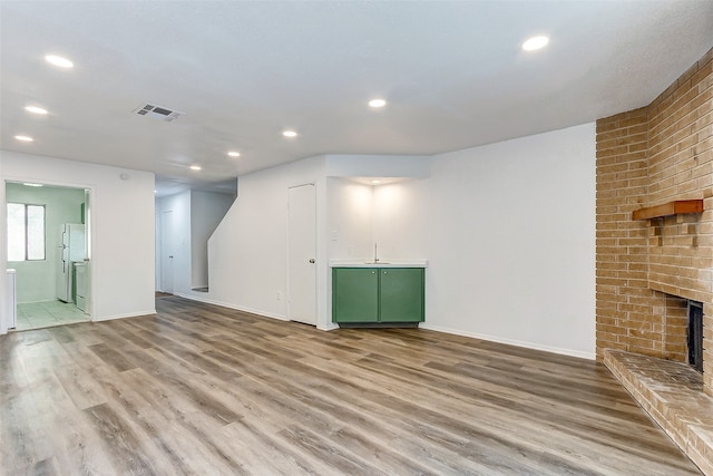 unfurnished living room with a fireplace and light wood-type flooring