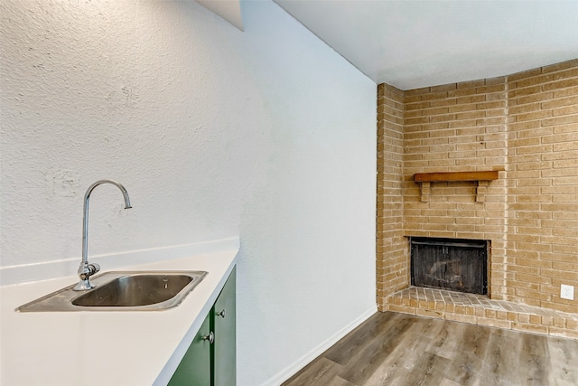 kitchen with sink, a fireplace, hardwood / wood-style flooring, and green cabinets