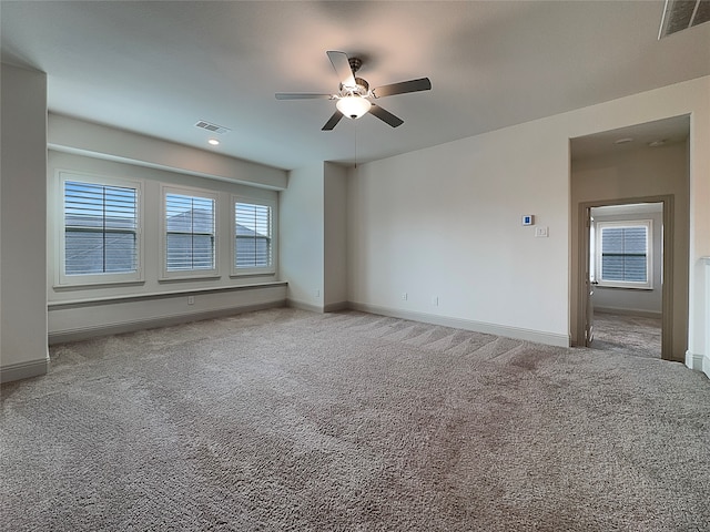 carpeted spare room featuring plenty of natural light and ceiling fan