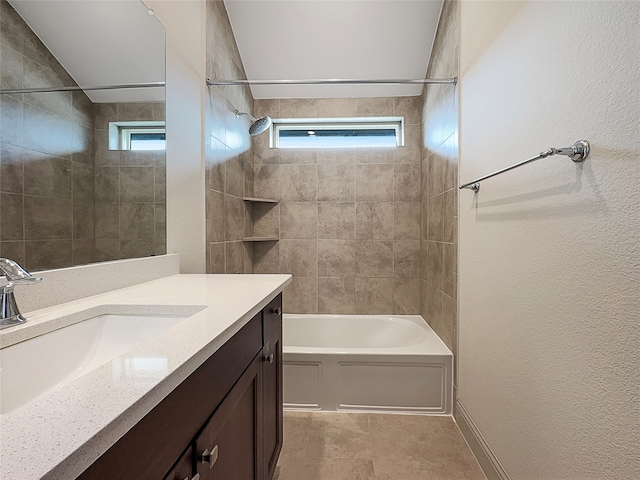 bathroom featuring plenty of natural light, vanity, and tiled shower / bath