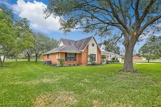 view of side of property with central AC and a yard