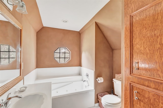 bathroom featuring lofted ceiling, a tub to relax in, toilet, and vanity