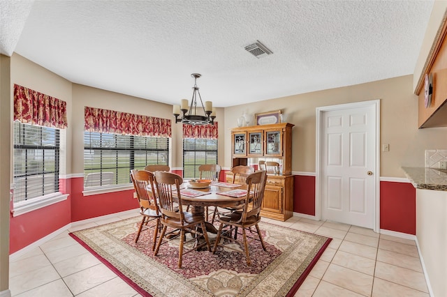 tiled dining room featuring a textured ceiling and a notable chandelier