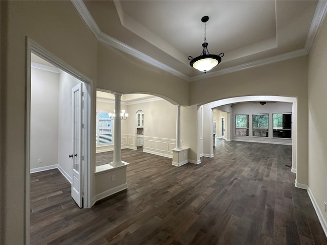 hallway featuring a tray ceiling, dark hardwood / wood-style floors, crown molding, and decorative columns