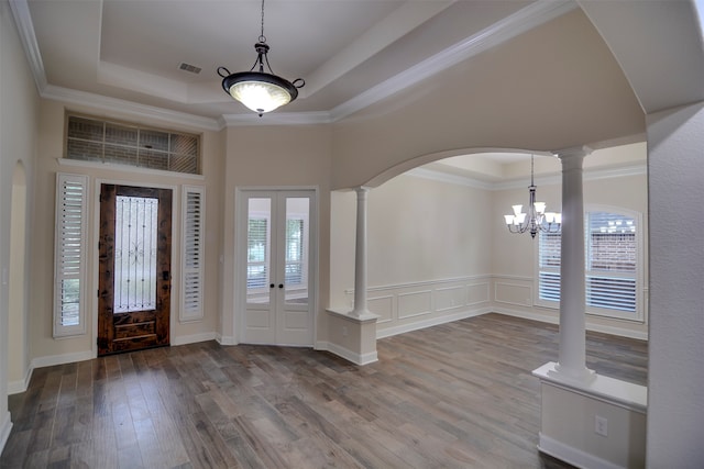 foyer with ornate columns, an inviting chandelier, hardwood / wood-style floors, crown molding, and a tray ceiling