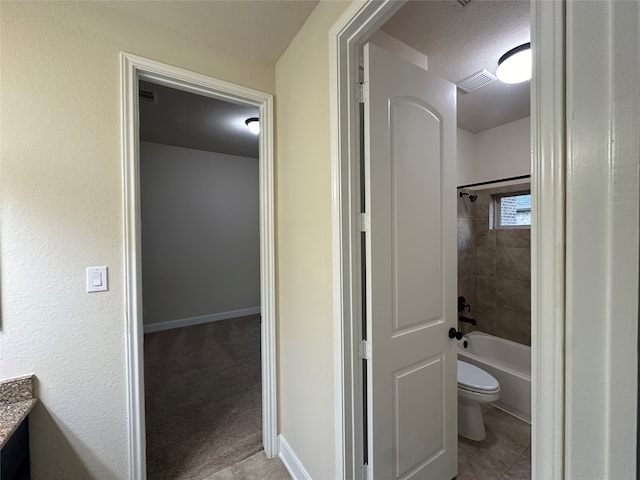 full bathroom featuring tile patterned flooring, tiled shower / bath, a textured ceiling, vanity, and toilet