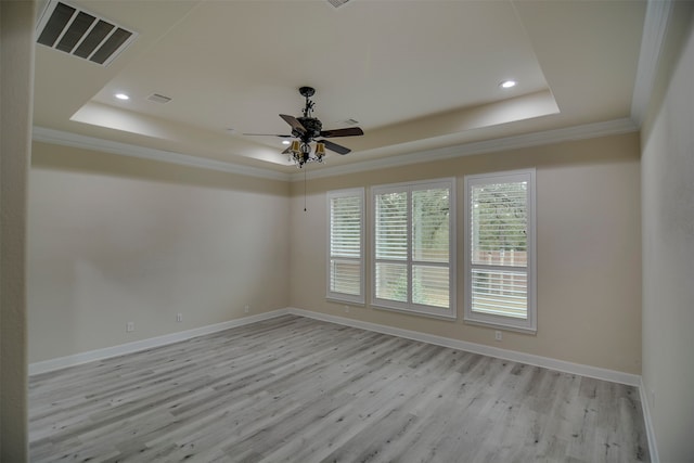 empty room with ornamental molding, light hardwood / wood-style floors, and a raised ceiling