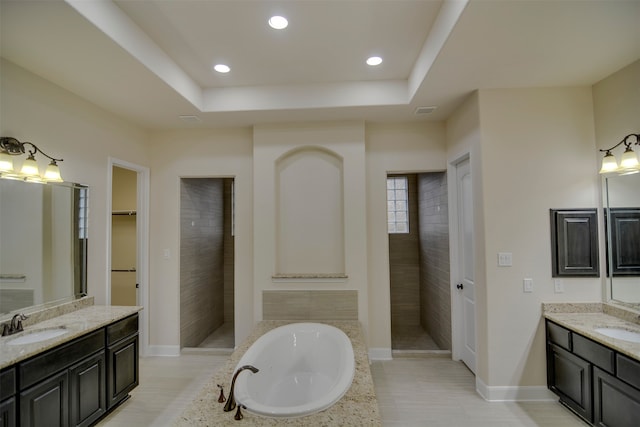 bathroom with a washtub, vanity, and a raised ceiling