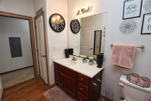 bathroom featuring toilet, electric panel, vanity, and wood-type flooring