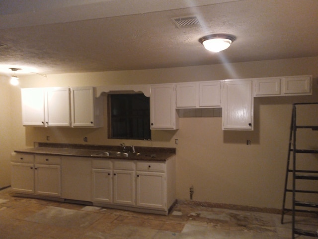 kitchen featuring white cabinetry, sink, and a textured ceiling