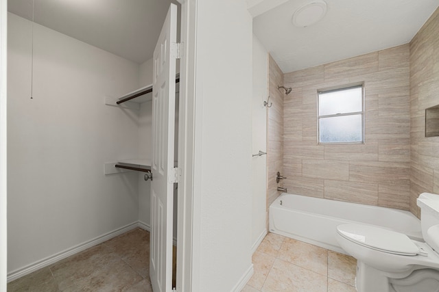 bathroom featuring tile patterned flooring, tiled shower / bath, and toilet