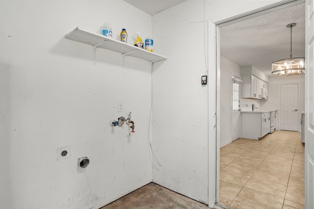 laundry room with a textured ceiling, an inviting chandelier, and hookup for an electric dryer