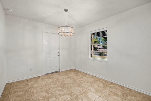 empty room with a textured ceiling, a chandelier, and light tile patterned floors