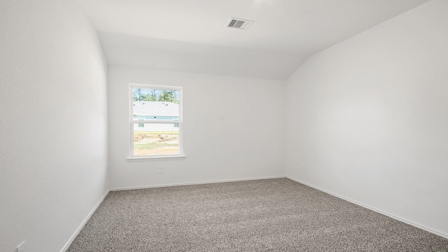 carpeted spare room with vaulted ceiling