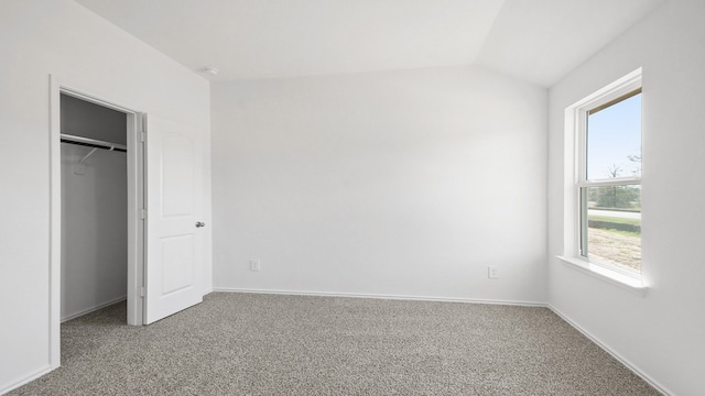 unfurnished bedroom with carpet flooring, multiple windows, a closet, and vaulted ceiling