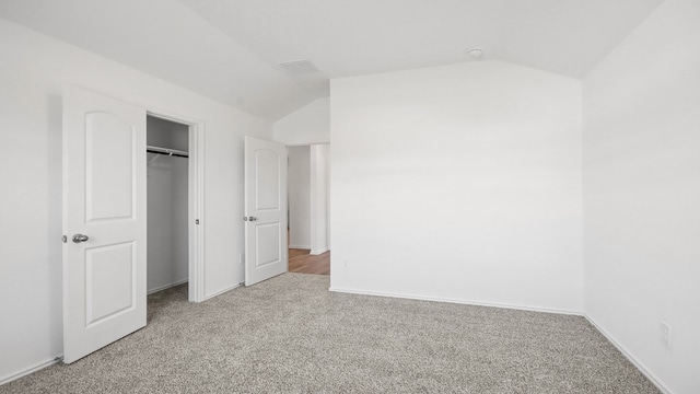 unfurnished bedroom with a closet, carpet, and lofted ceiling