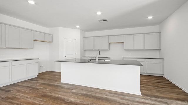 kitchen with sink, dark wood-type flooring, and an island with sink