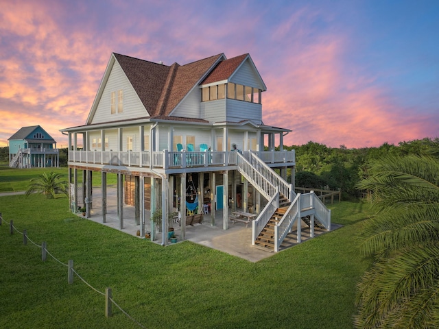 back house at dusk with a lawn, a deck, and a patio area