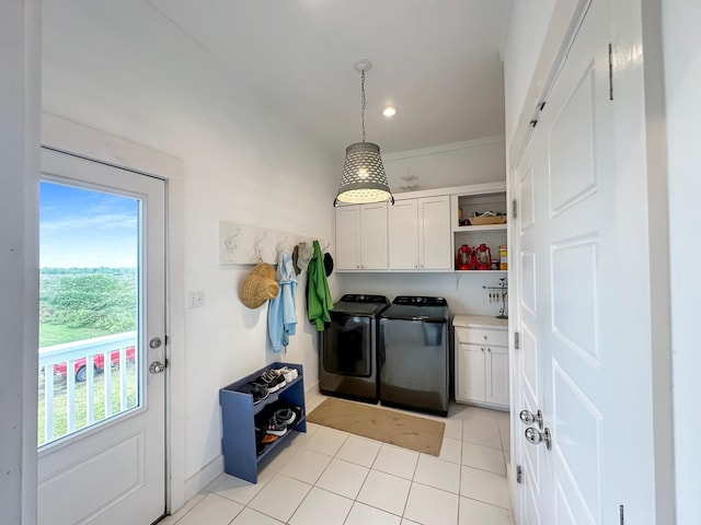 laundry room featuring washing machine and dryer, cabinets, and light tile patterned floors