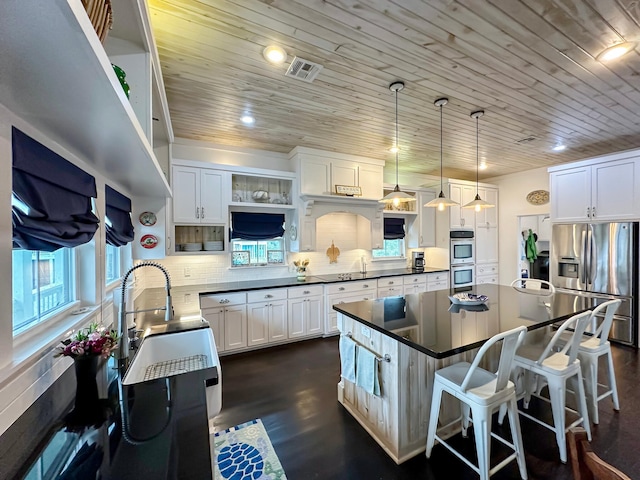 kitchen with stainless steel appliances, decorative backsplash, hanging light fixtures, dark hardwood / wood-style floors, and white cabinetry