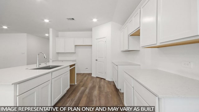 kitchen with dark hardwood / wood-style flooring, sink, a center island with sink, and white cabinets