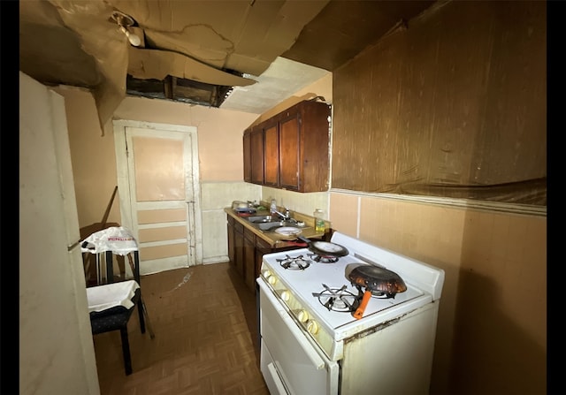 kitchen featuring dark parquet flooring, gas range gas stove, and sink