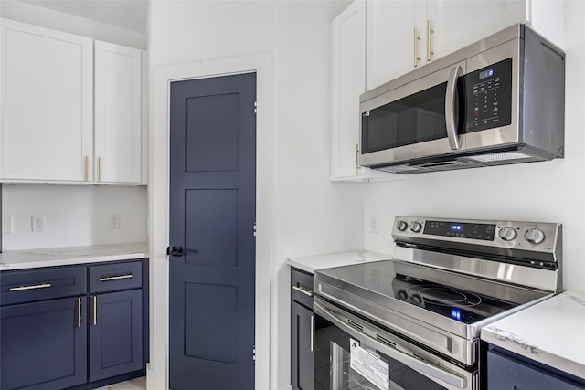 kitchen with stainless steel appliances, white cabinetry, and blue cabinets