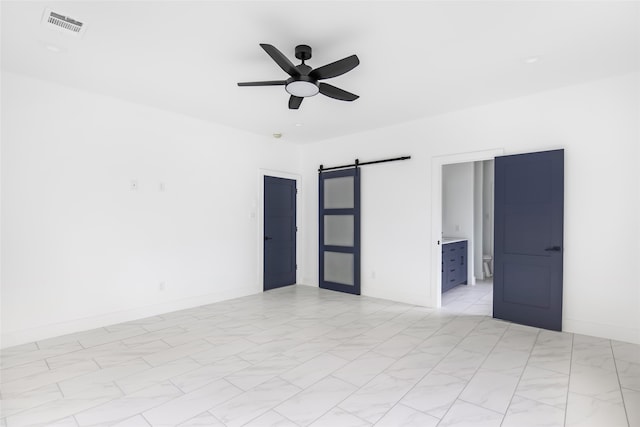 empty room featuring a barn door and ceiling fan