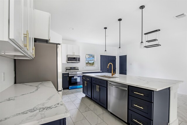 kitchen with stainless steel appliances, white cabinets, sink, a kitchen island with sink, and decorative light fixtures