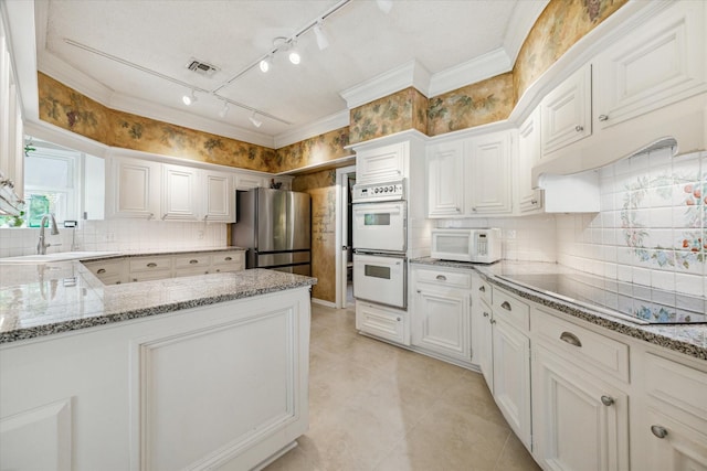 kitchen featuring white appliances, backsplash, white cabinets, sink, and light stone countertops