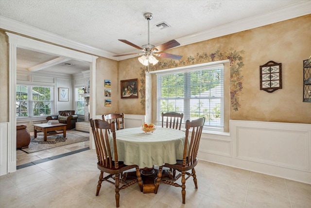 tiled dining room with a textured ceiling, plenty of natural light, ceiling fan, and ornamental molding