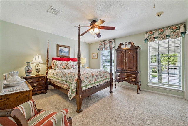 carpeted bedroom featuring ceiling fan and a textured ceiling