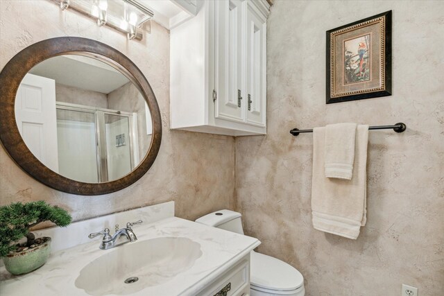 bathroom with vanity, toilet, and a shower with door