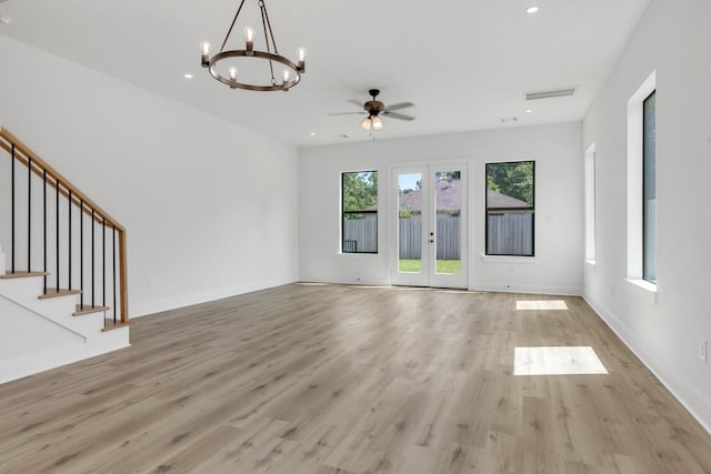 unfurnished living room featuring ceiling fan with notable chandelier, light wood-type flooring, and french doors