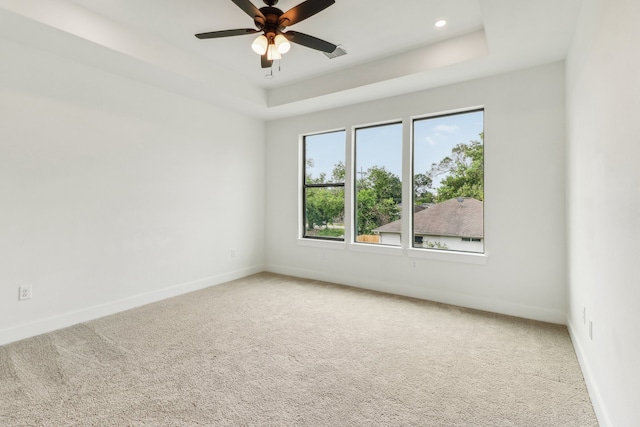 empty room with carpet flooring, ceiling fan, and a raised ceiling